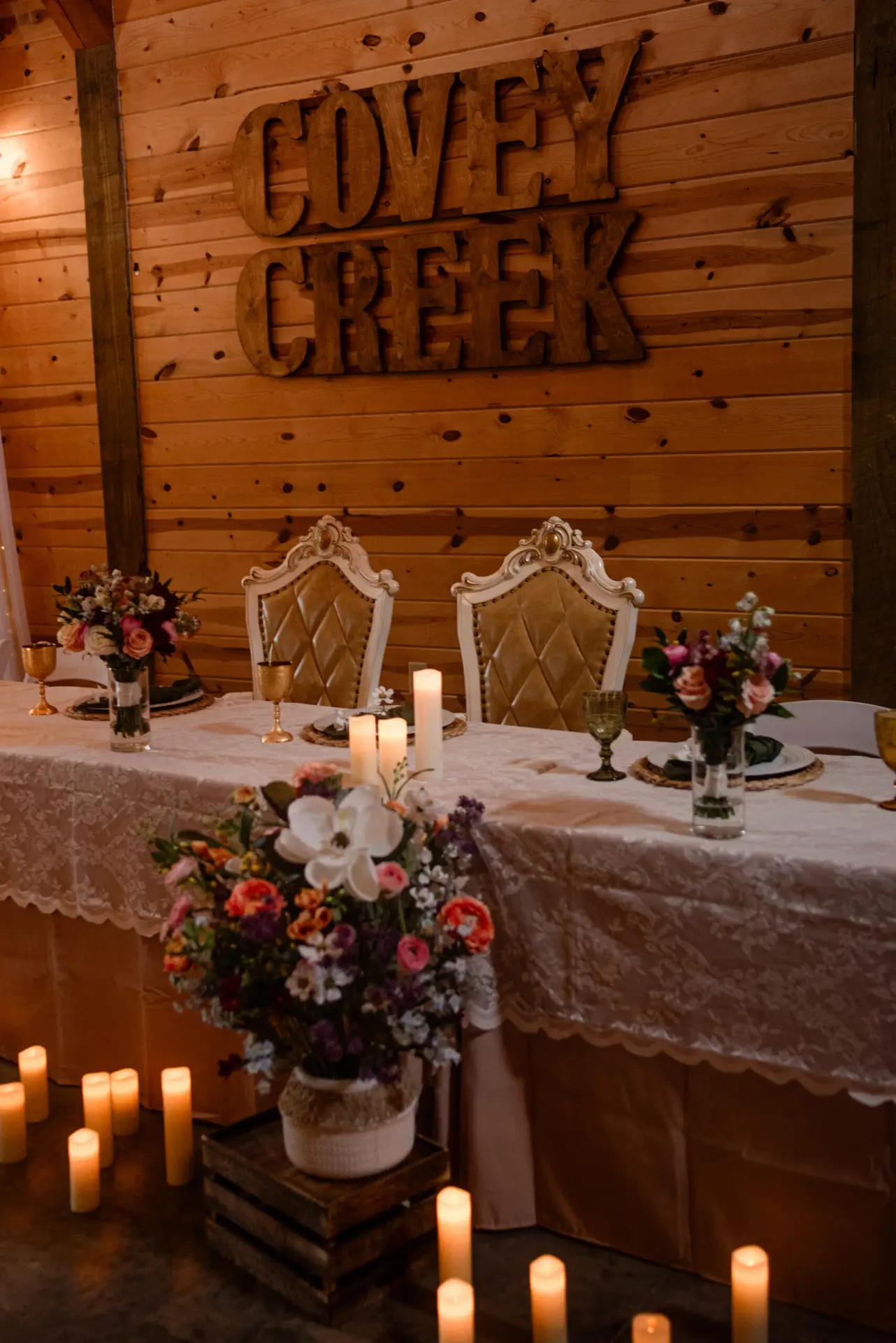 Sweetheart chairs at Rachael & Ben’s lace head table beneath the Covey Creek barn wood sign.