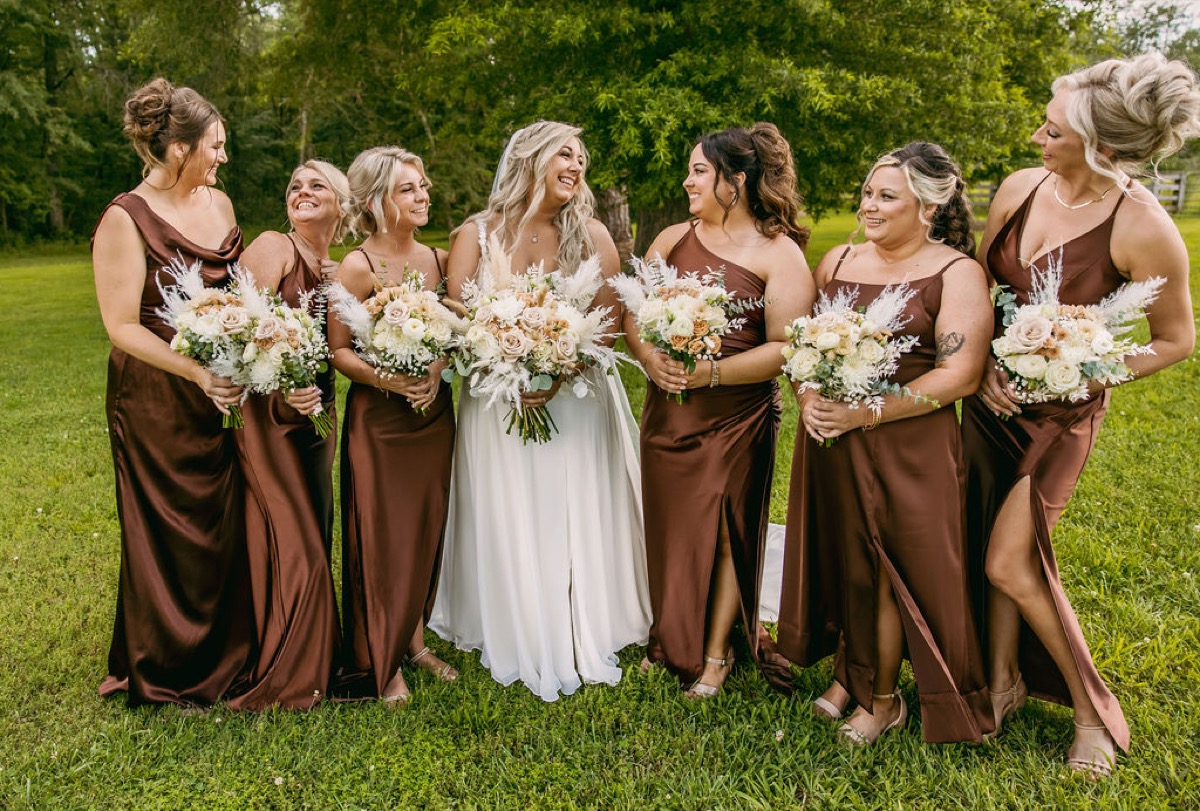 Alexis & Logan: Alexis laughs with six bridesmaids in chocolate satin on the green lawn at Covey Creek