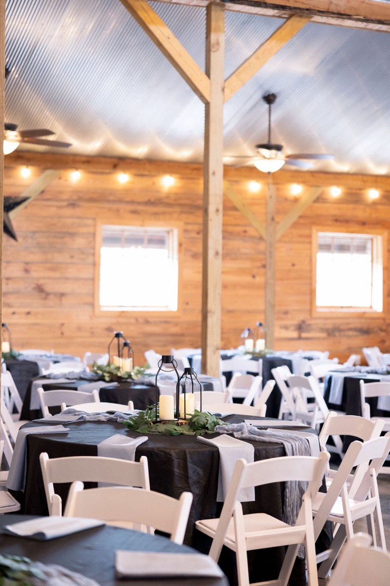 Indoor reception at Covey Creek for Carly & Lucas with round tables, black cloths, lanterns, and string lights