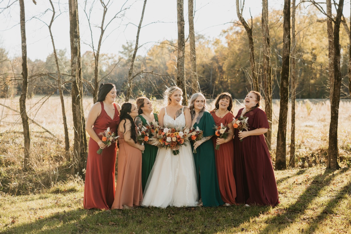 Danika laughs with bridesmaids in autumn jewel-tone dresses for Danika & Troy at Covey Creek