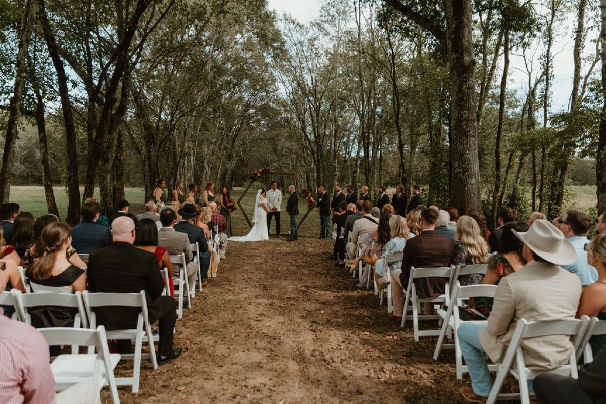 Guests face Elizabeth & Ashton under a hexagonal floral arbor during their wooded ceremony at Covey Creek