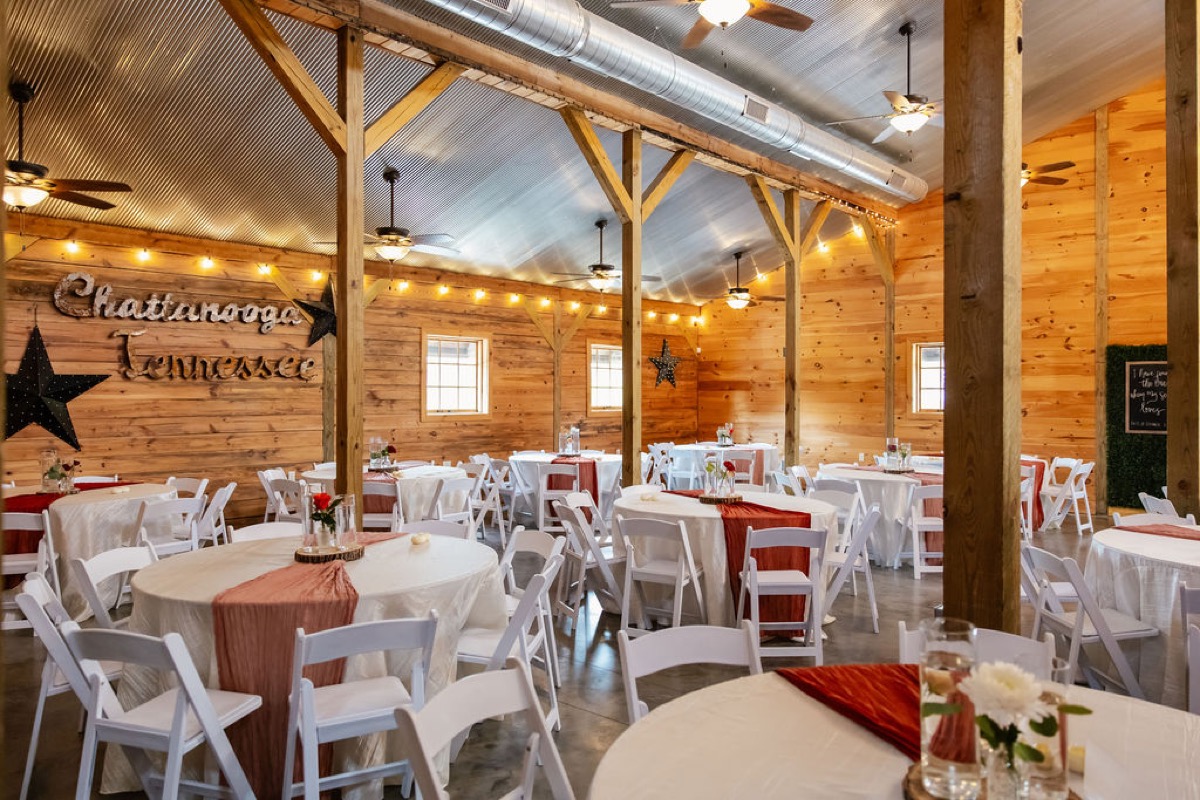Erica & Randall indoor reception at Covey Creek—round tables, terracotta runners, Chattanooga Tennessee wall sign