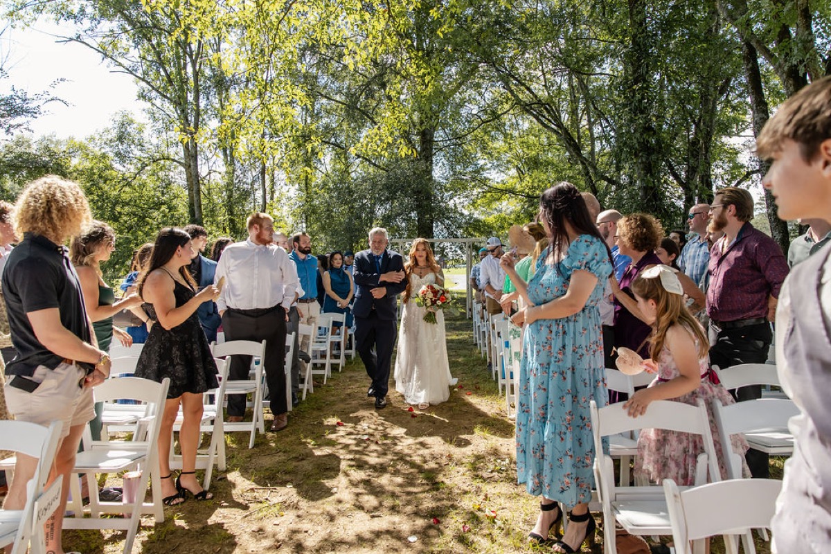 Erica & Randall’s bride walks the Tunnel of Love aisle past guests toward the arbor at Covey Creek