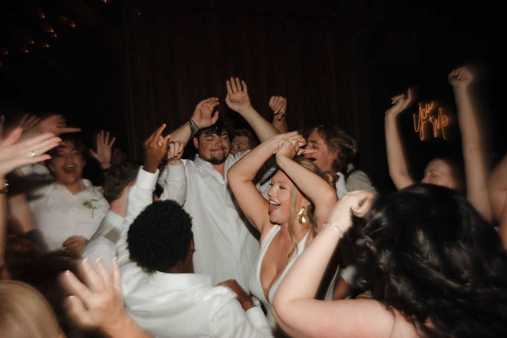Hailey dances arms raised with guests under a You + Me neon sign at Hailey & Joseph's Covey Creek reception