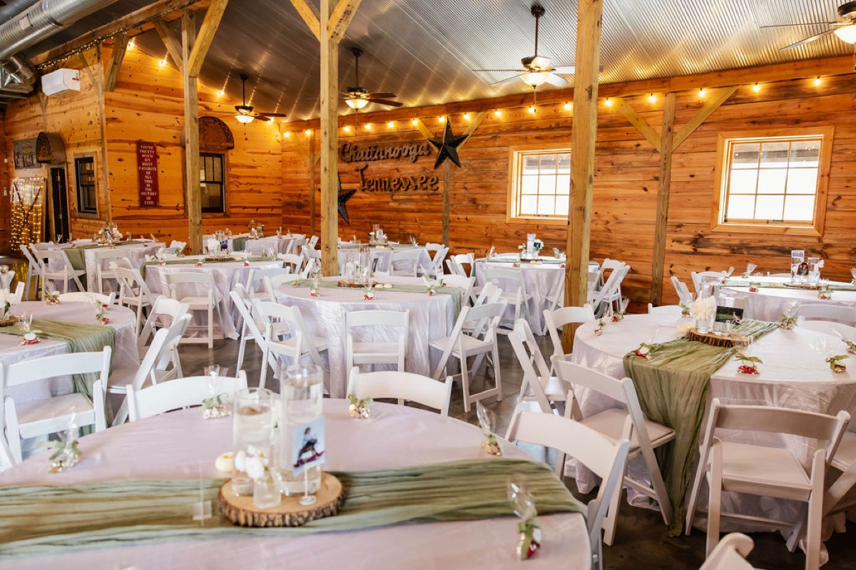Hannah & Nicholas reception barn at Covey Creek with sage runners, string lights, and a Chattanooga Tennessee wall sign.