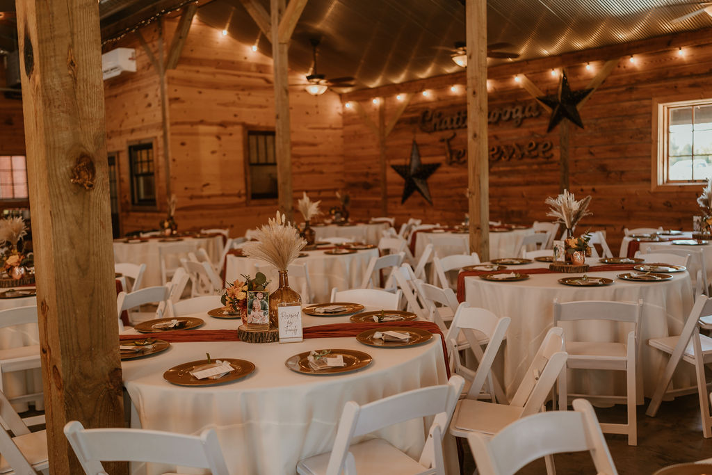 JJ & Will barn reception set with gold chargers, pampas bottles, and string lights at Covey Creek