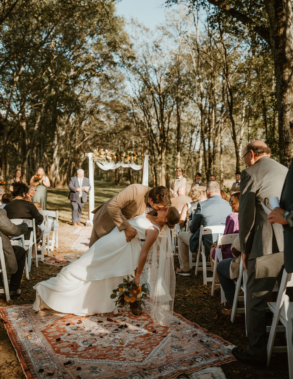 JJ & Will: Will dips JJ for a kiss on the rug aisle under the Tunnel of Love arbor at Covey Creek