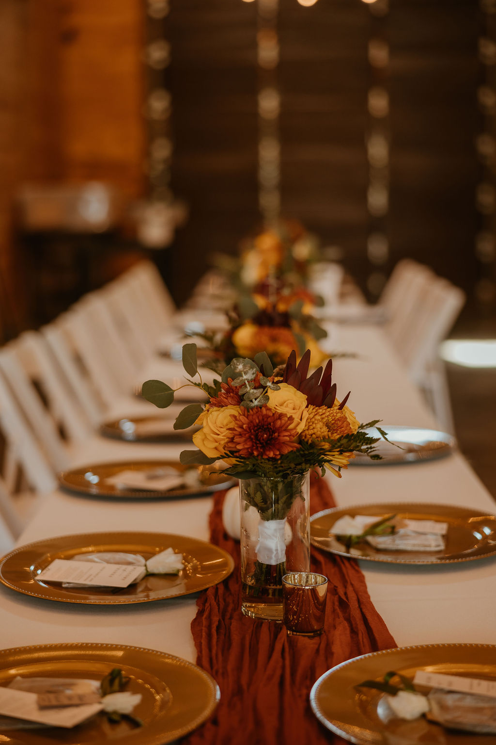 JJ & Will reception table with fall florals, gold chargers, and terracotta runner indoors at Covey Creek