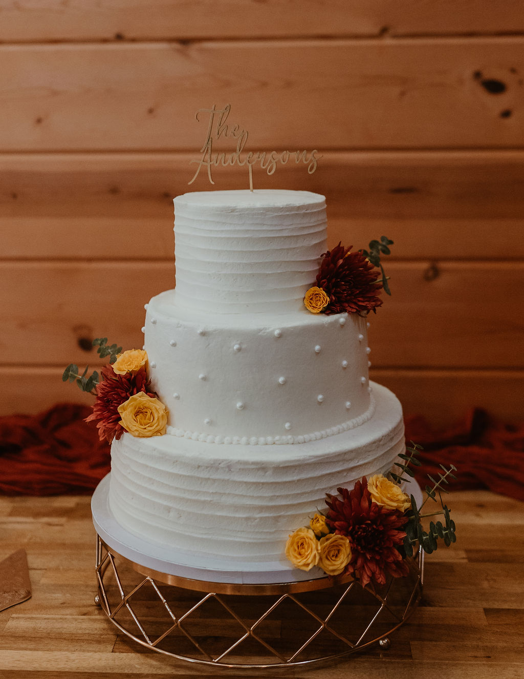 JJ & Will three-tier white cake with fall flowers and The Andersons topper indoors at Covey Creek
