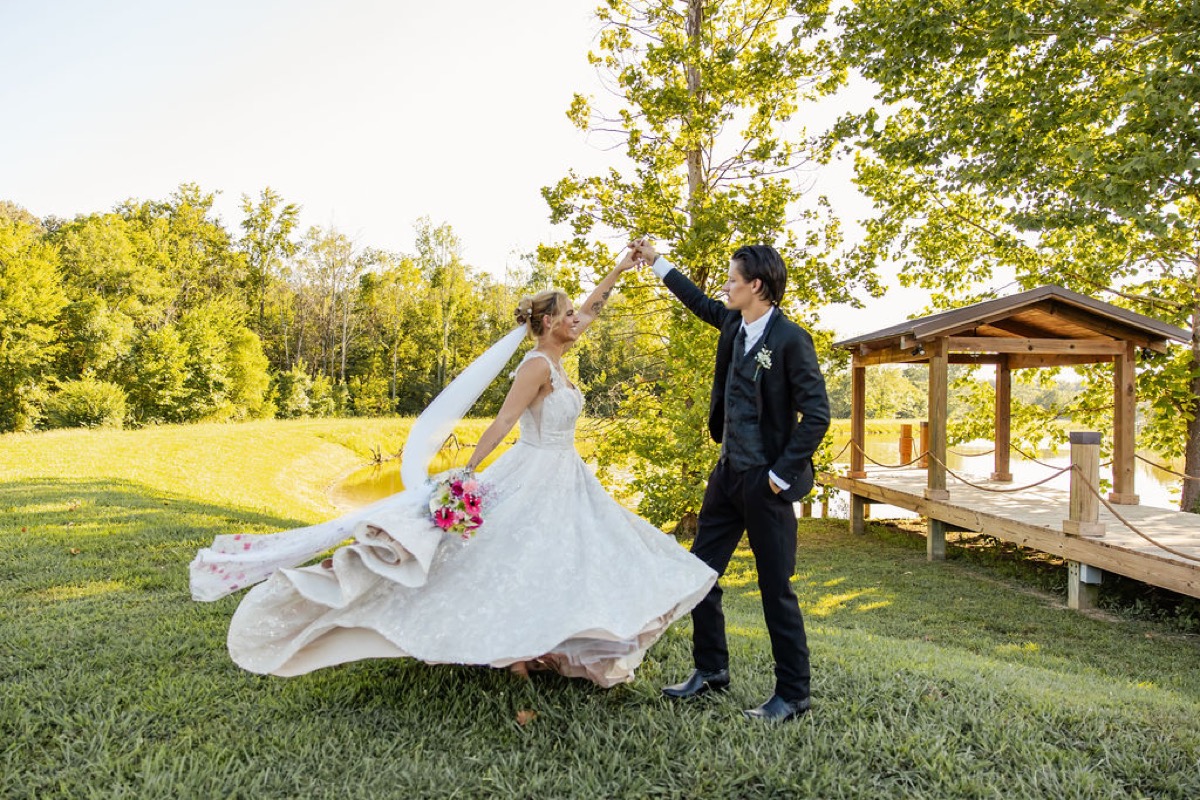 Nathan twirls Kolbe on the lawn by the pond pavilion at Covey Creek during Kolbe & Nathan's wedding