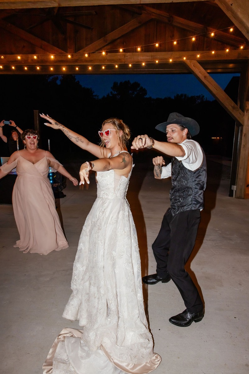 Kolbe & Nathan dance under pavilion string lights; she wears red heart sunglasses at Covey Creek