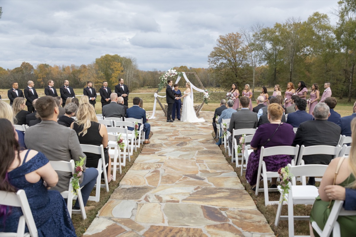 Kristen & Dalton exchange vows down the flagstone aisle with wedding party under a hexagonal arbor at Covey Creek