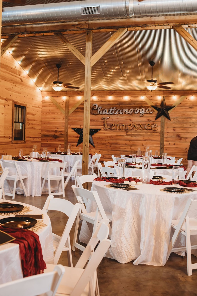 Barn reception hall with white tables, burgundy runners, and string lights for Lauren & Alex at Covey Creek