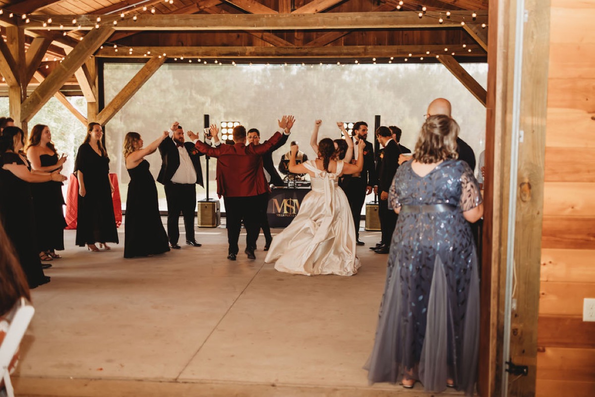 Lauren of Lauren & Alex dances with guests under string lights in the pavilion at Covey Creek