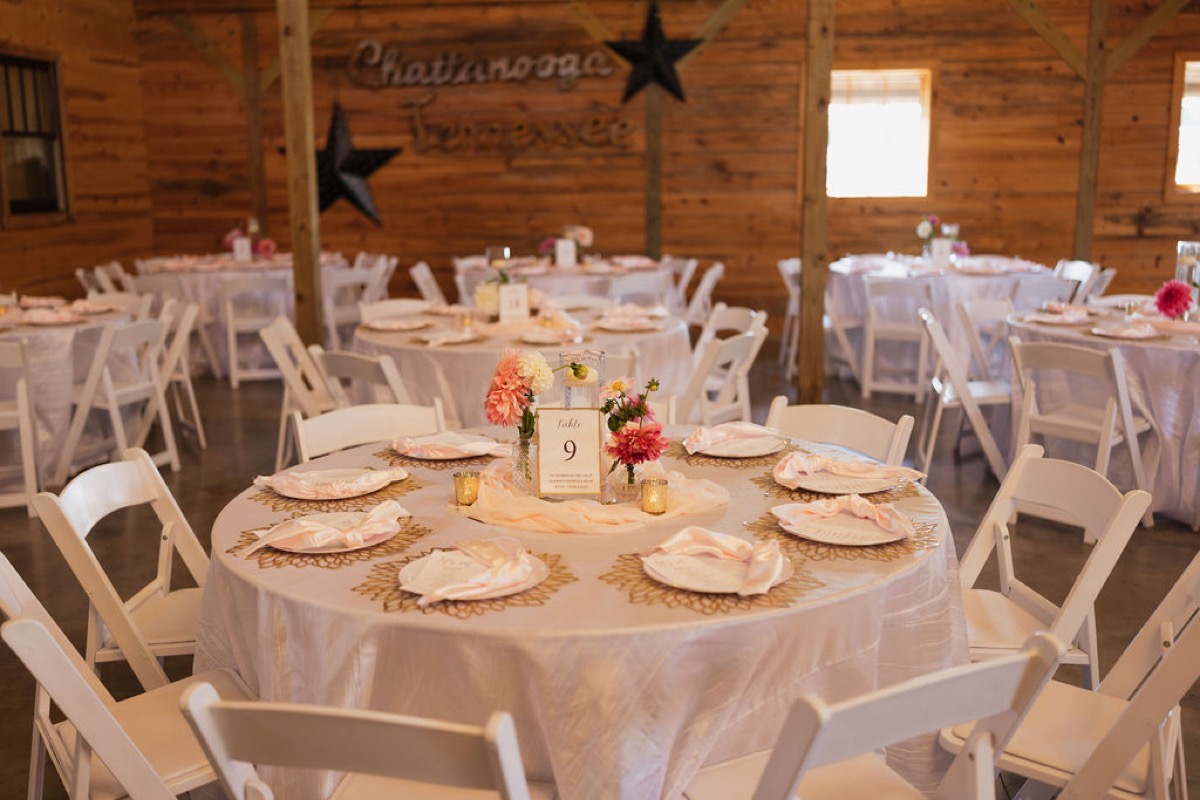 Lilly & Jackson Table 9 at Covey Creek with gold chargers, pink dahlias, floating candle, and wood barn walls