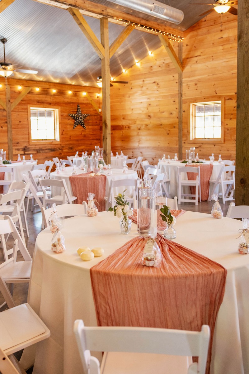 Raven & Jackson indoor reception at Covey Creek with round tables, terracotta runners, bud vases, and string lights