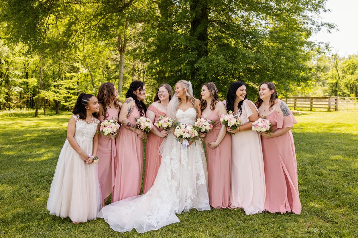 Raven poses with dusty-rose bridesmaids and a flower girl on the lawn at Covey Creek for Raven & Jackson
