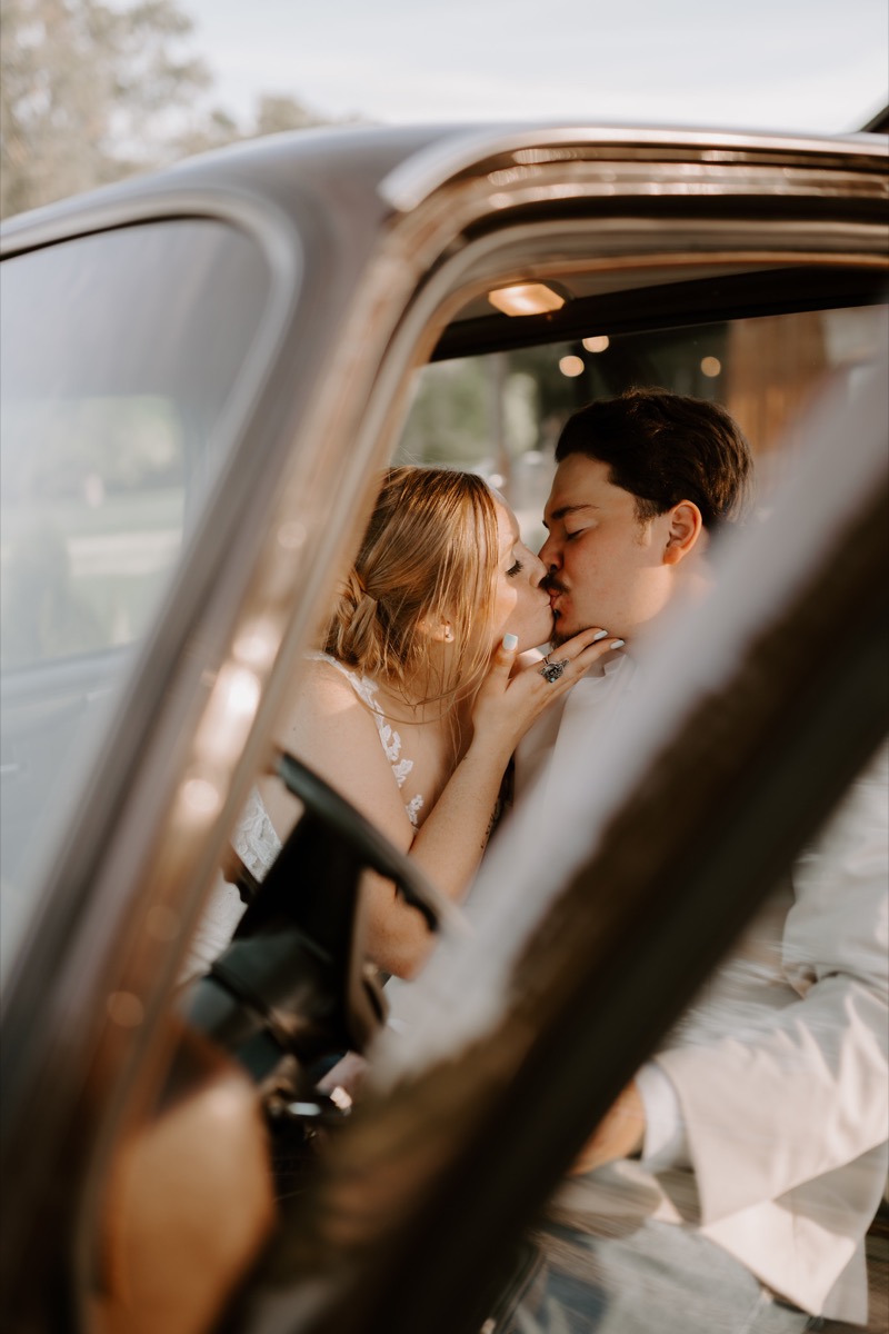 Shay & Wyatt share a close kiss through the open window of a vintage car at golden hour at Covey Creek.