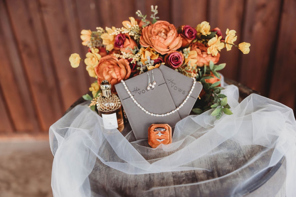 Tori & Tim wedding flat lay with autumn bouquet, vow books, pearls, and rings at Covey Creek