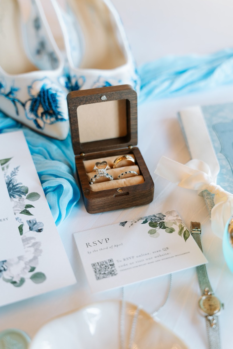 Rings in a wood box with blue-embroidered heels and RSVP card for Kyley & Nick at Covey Creek