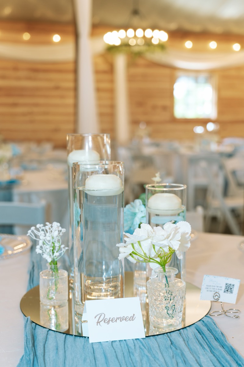 Floating candles and baby's breath centerpiece on a blue runner for Kyley & Nick at Covey Creek