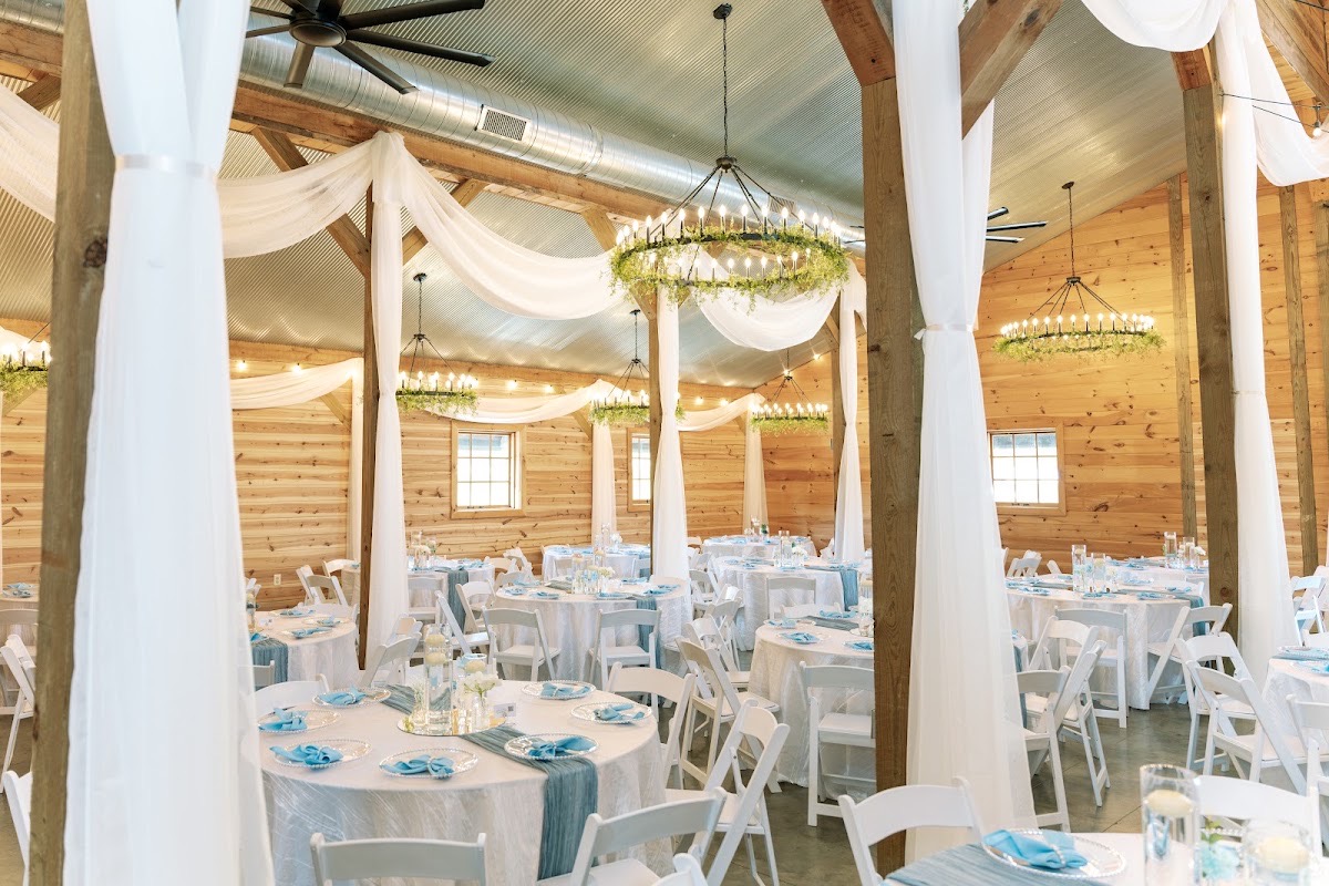 Wide view of draped barn tables with floating-candle centerpieces for Kyley & Nick at Covey Creek