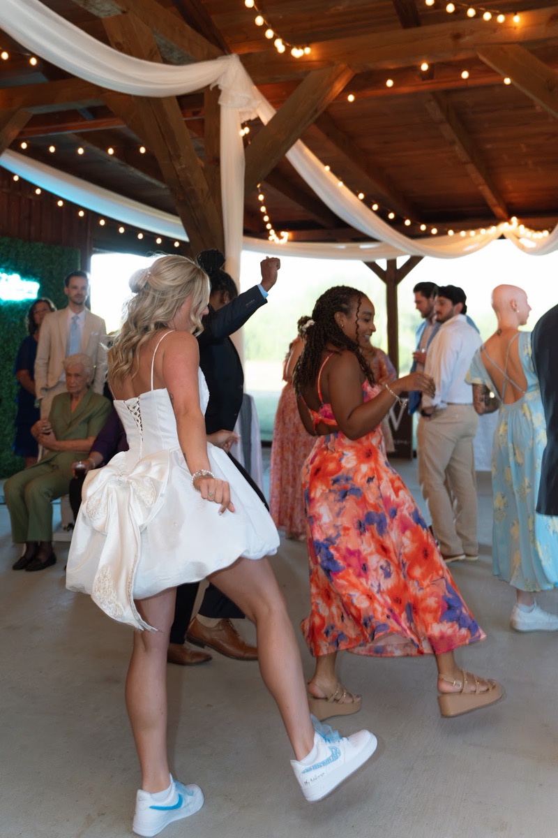 Kyley dances in Nike sneakers beside a guest at Kyley & Nick's pavilion reception at Covey Creek
