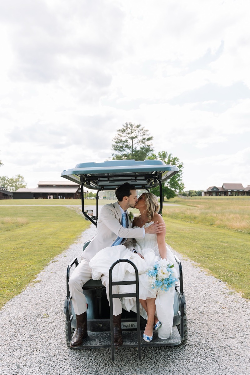 Kyley & Nick kiss on the back of a light blue golf cart along the gravel path at Covey Creek