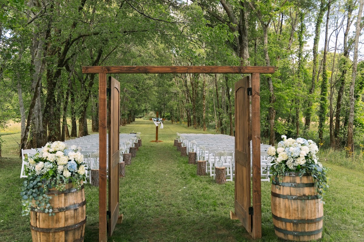 Open wooden doors and barrel florals lead to Kyley & Nick's Tunnel of Love ceremony at Covey Creek