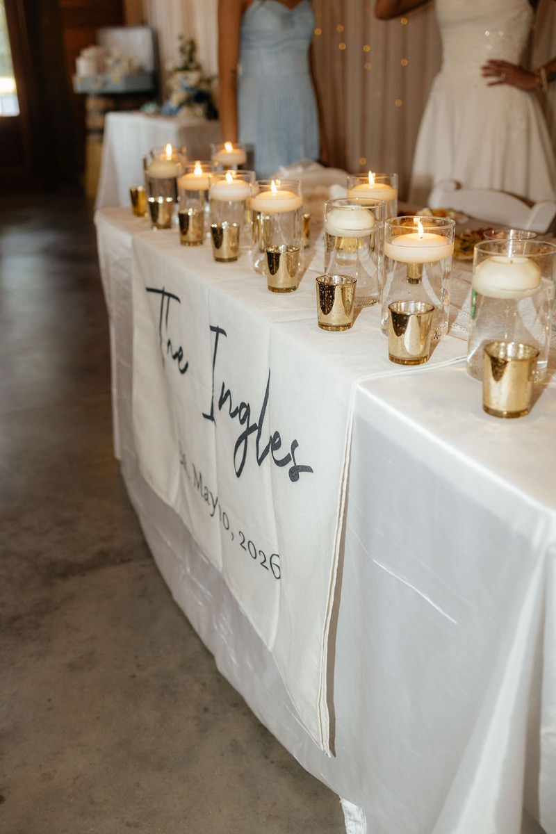 Kylie & Mason sweetheart table with The Ingles banner, floating candles, and fairy lights at Covey Creek