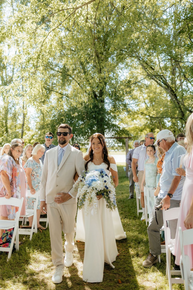 Kylie & Mason bridal processional down the Tunnel of Love aisle under spring tree canopy at Covey Creek