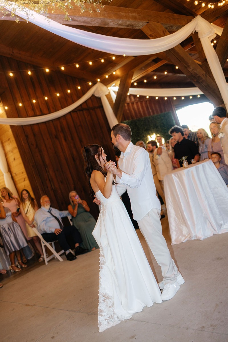 Kylie & Mason dance under draped beams and Edison lights at their Covey Creek indoor reception