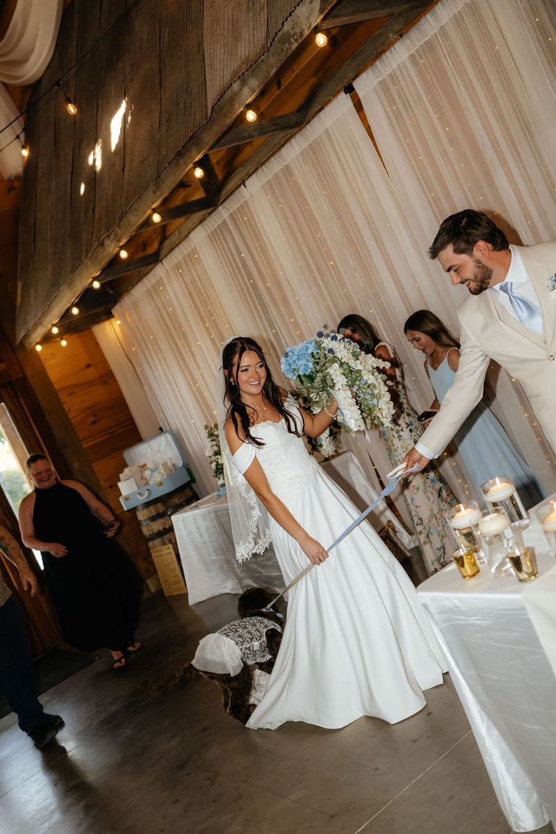 Kylie & Mason walk their dog in a lace dress through the warm indoor reception at Covey Creek