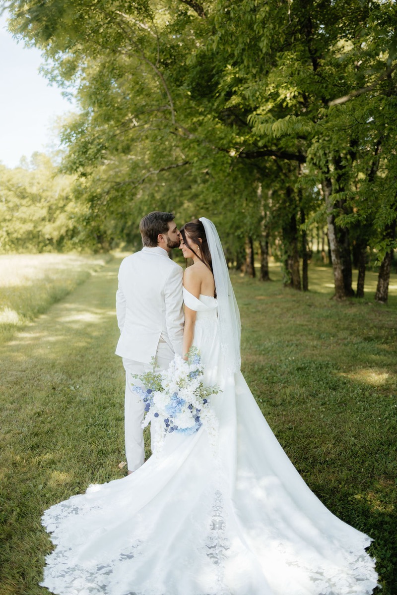 Kylie & Mason share a forehead kiss beside the Tunnel of Love tree line in spring light at Covey Creek