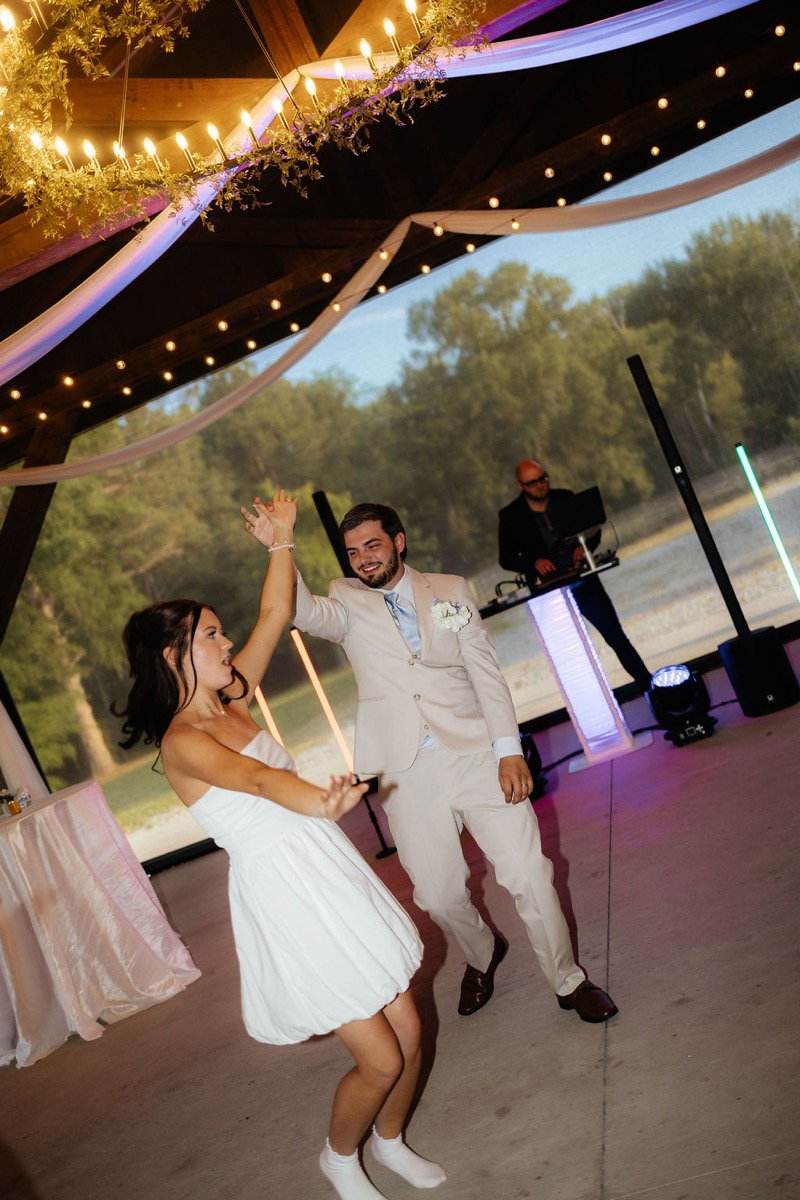 Kylie & Mason dance near the DJ under purple lights at their evening Covey Creek indoor reception
