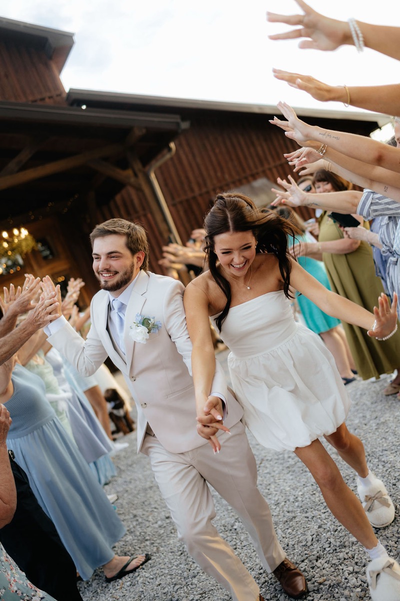 Kylie & Mason run a high-five exit in short dress and tan suit on the Covey Creek gravel path