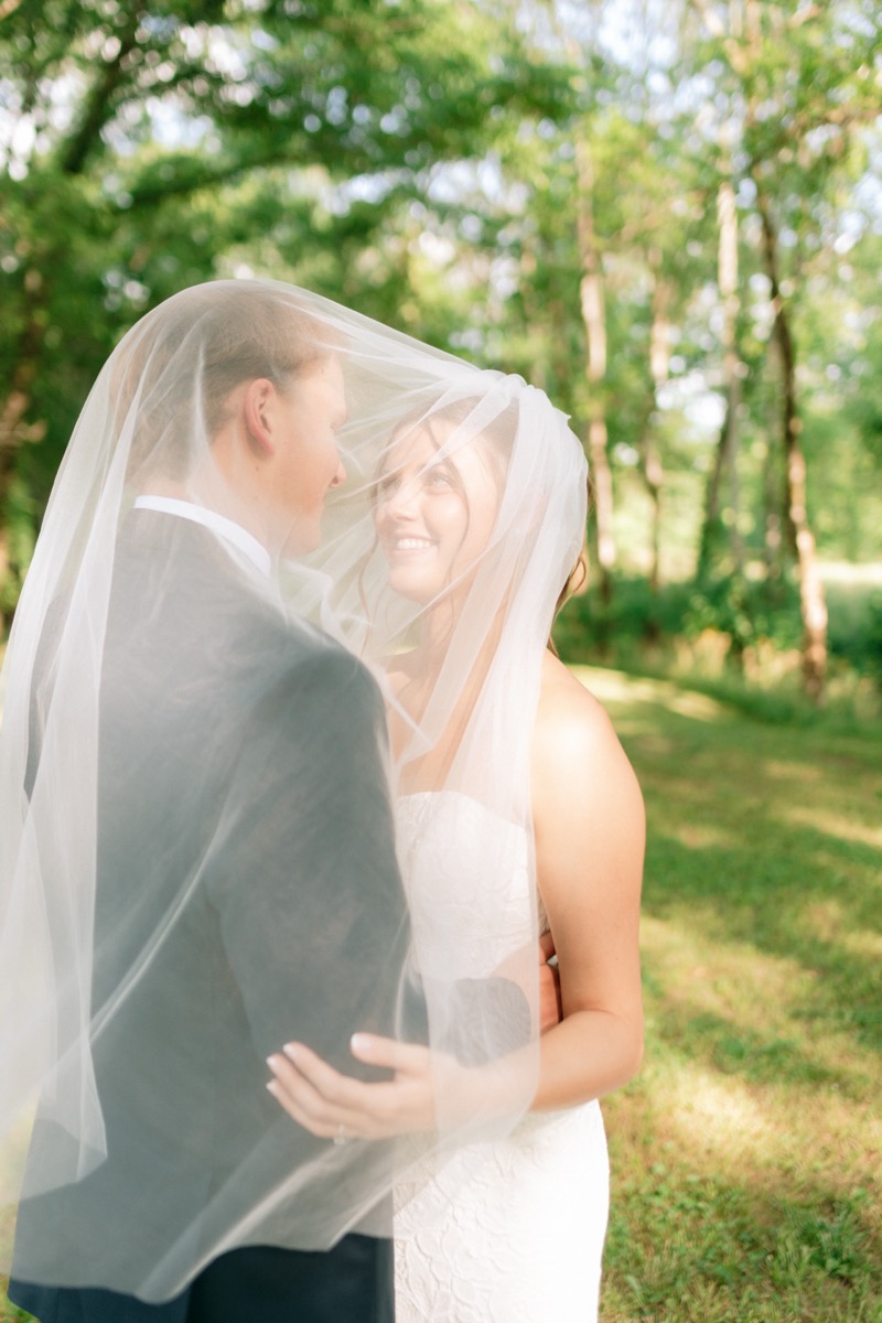 Rachel & Ben embrace under her sheer veil in soft spring woodland light outdoors at Covey Creek.