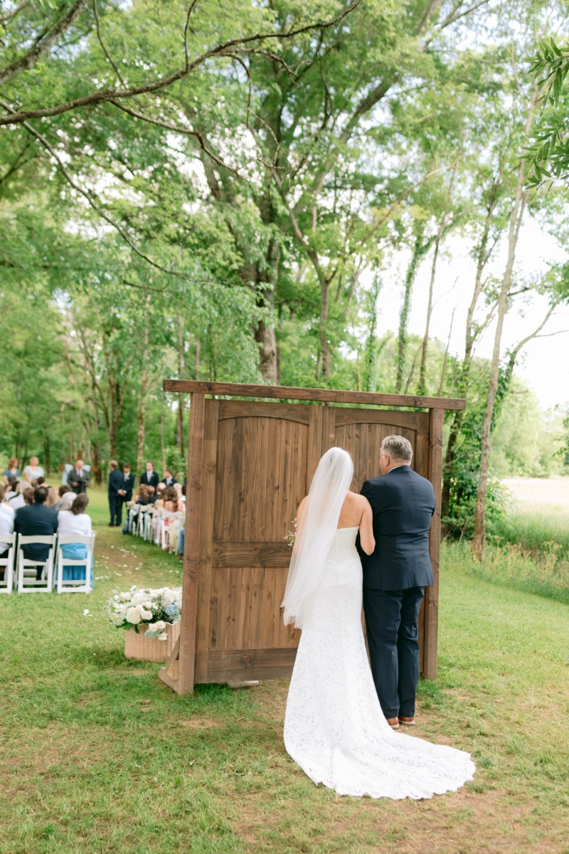 Rachel & Ben's Tunnel of Love ceremony framed by wooden aisle doors and spring greenery at Covey Creek.